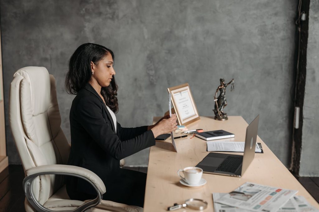 A focused businesswoman in formal attire works at her desk in a contemporary office setting.